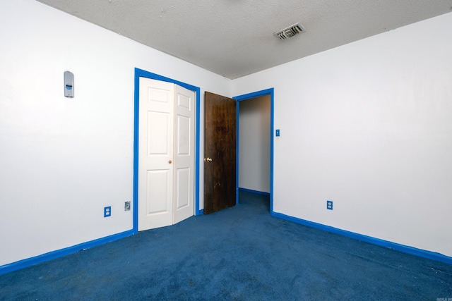 unfurnished bedroom featuring dark colored carpet, a textured ceiling, and a closet