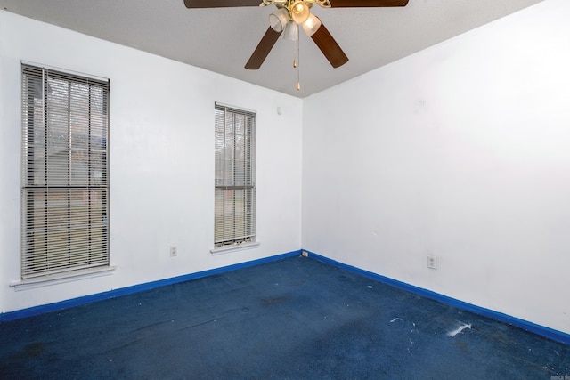 spare room with a textured ceiling, dark carpet, and ceiling fan