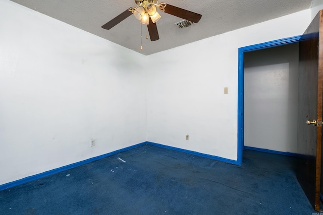 unfurnished room with ceiling fan, dark carpet, and a textured ceiling