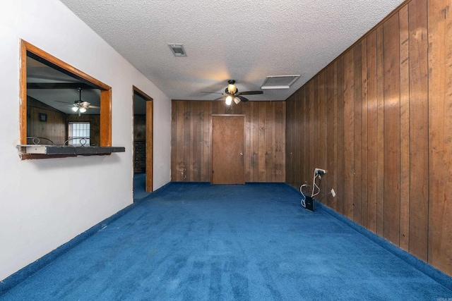 carpeted empty room featuring ceiling fan and wood walls