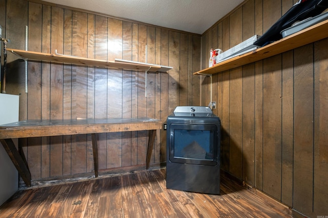 laundry area featuring a textured ceiling, washer / clothes dryer, dark hardwood / wood-style floors, and wood walls