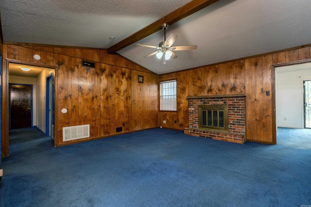 unfurnished living room with wood walls, dark carpet, and a fireplace