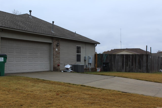 view of side of property with a lawn, cooling unit, and a garage