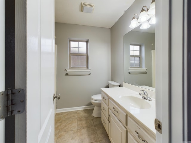 bathroom with tile patterned floors, vanity, a healthy amount of sunlight, and toilet