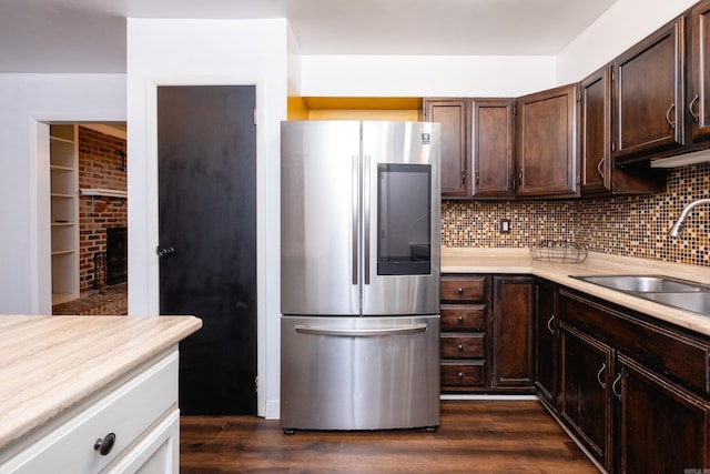 kitchen with backsplash, dark wood-type flooring, sink, dark brown cabinets, and stainless steel refrigerator