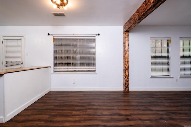 empty room featuring beamed ceiling and dark hardwood / wood-style floors