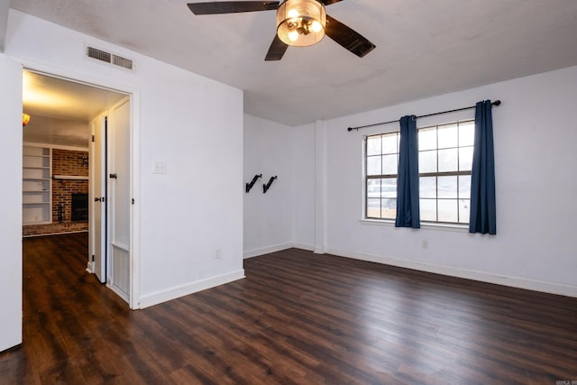 empty room featuring ceiling fan, a fireplace, built in features, and dark hardwood / wood-style floors