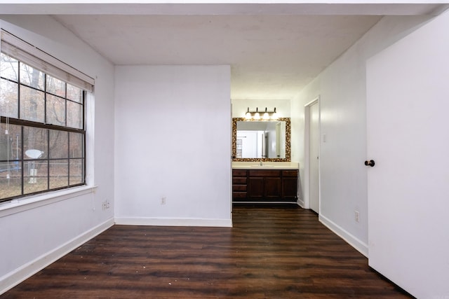 interior space featuring ensuite bathroom, sink, and dark wood-type flooring