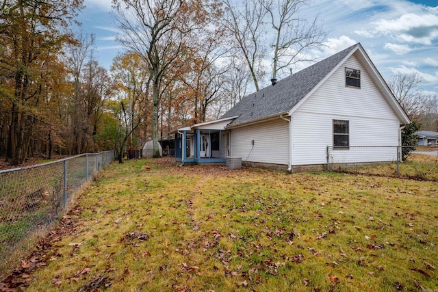 exterior space with central air condition unit, a sunroom, and a yard