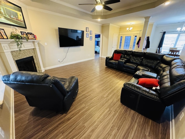 living room with a high end fireplace, hardwood / wood-style floors, ceiling fan with notable chandelier, and ornamental molding