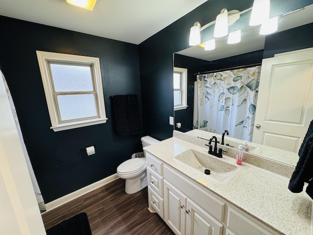 bathroom with plenty of natural light, vanity, wood-type flooring, and toilet