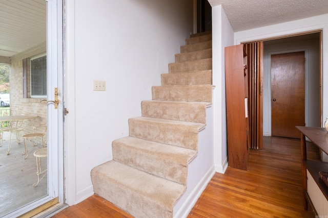 stairway with a textured ceiling and hardwood / wood-style flooring