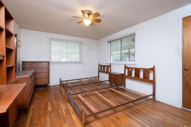 bedroom with wood-type flooring, a textured ceiling, and ceiling fan