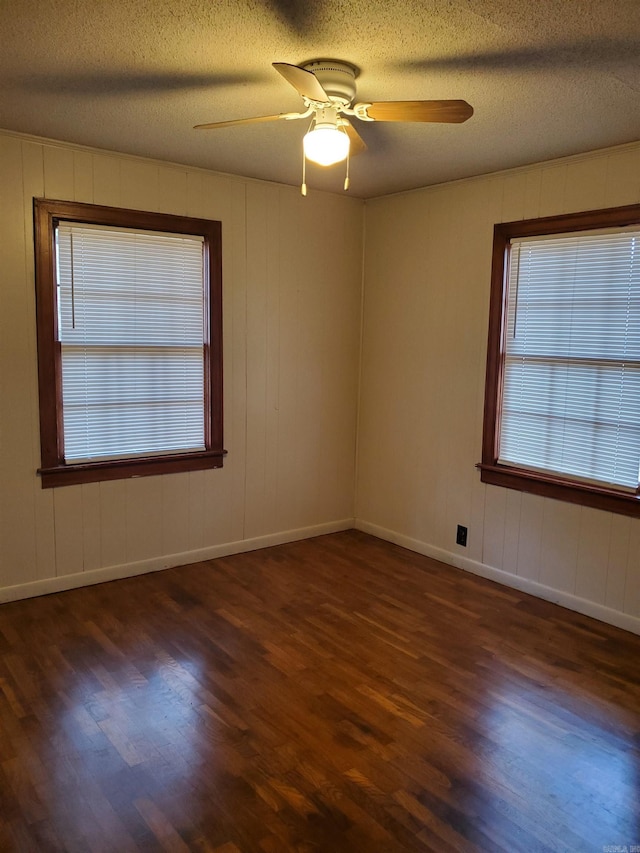 empty room featuring ceiling fan, dark wood-type flooring, and a textured ceiling