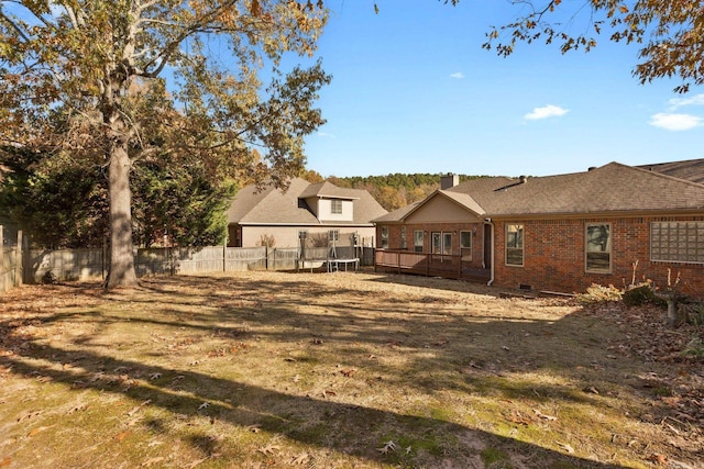 rear view of property featuring a lawn and a trampoline