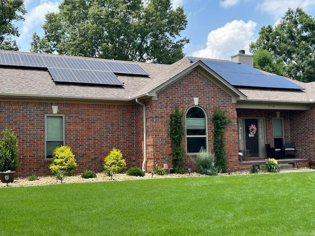 ranch-style home featuring a front yard and solar panels