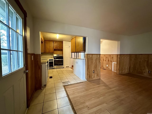 kitchen featuring light hardwood / wood-style floors, stainless steel range oven, and wooden walls