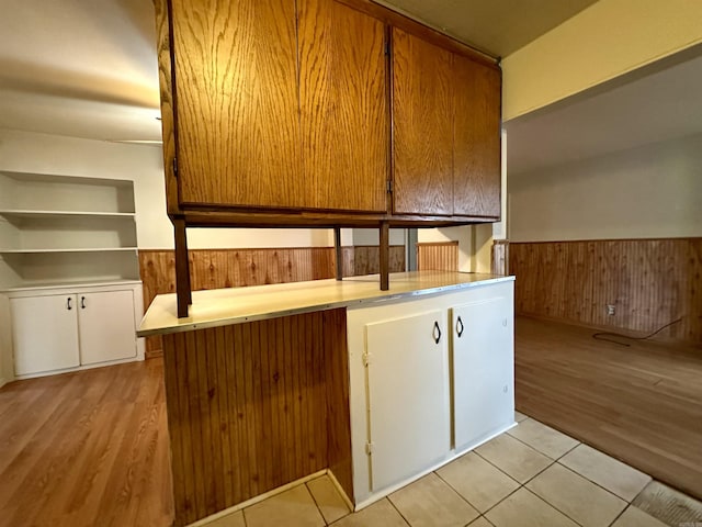 kitchen featuring wood walls, white cabinetry, and light hardwood / wood-style flooring