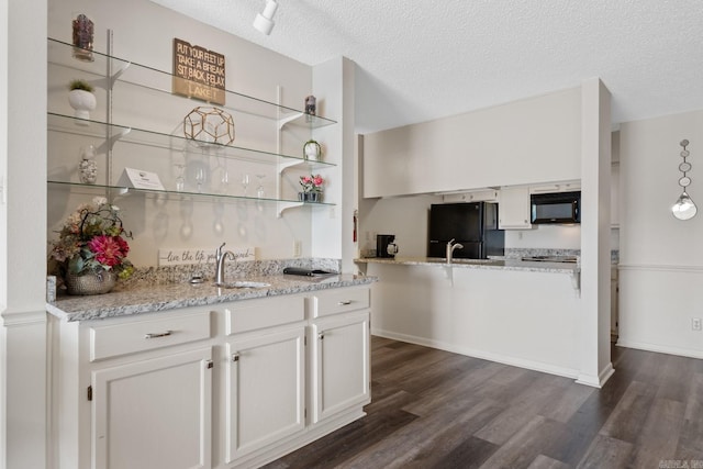 kitchen featuring white cabinetry, sink, dark wood-type flooring, a textured ceiling, and black appliances