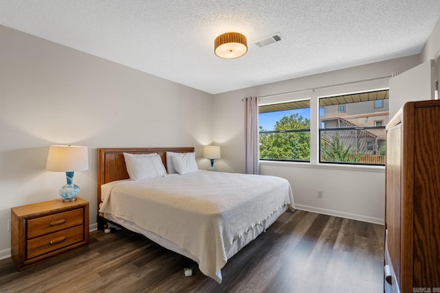 bedroom with a textured ceiling and dark hardwood / wood-style floors