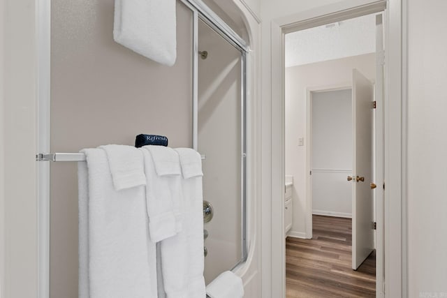 bathroom with vanity, shower / bath combination with glass door, wood-type flooring, and a textured ceiling