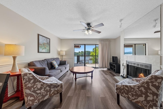 living room with ceiling fan, dark hardwood / wood-style flooring, and a textured ceiling