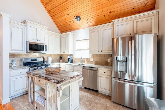 kitchen with a center island, light stone counters, stainless steel appliances, and vaulted ceiling