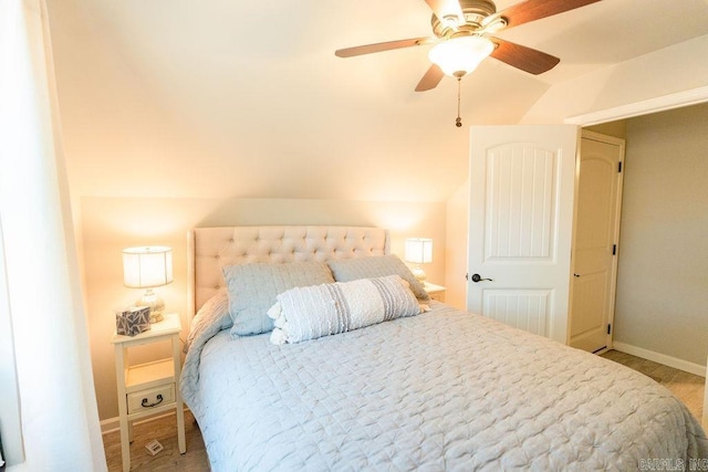 bedroom with ceiling fan, light hardwood / wood-style floors, and vaulted ceiling