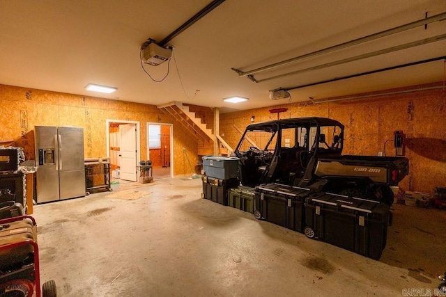 garage featuring stainless steel fridge with ice dispenser and a garage door opener