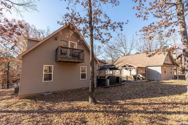 rear view of house featuring a gazebo, central AC unit, and a balcony