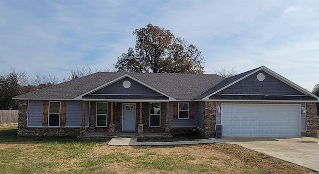 view of front of property featuring covered porch, a garage, and a front lawn