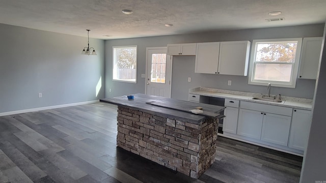 kitchen with decorative light fixtures, white cabinetry, plenty of natural light, and sink