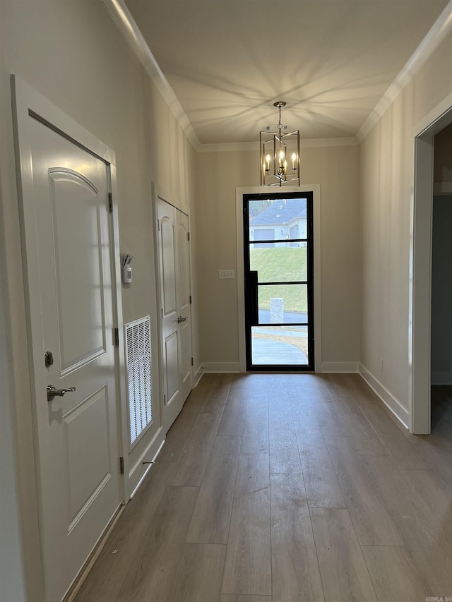 doorway with hardwood / wood-style flooring, a notable chandelier, and crown molding