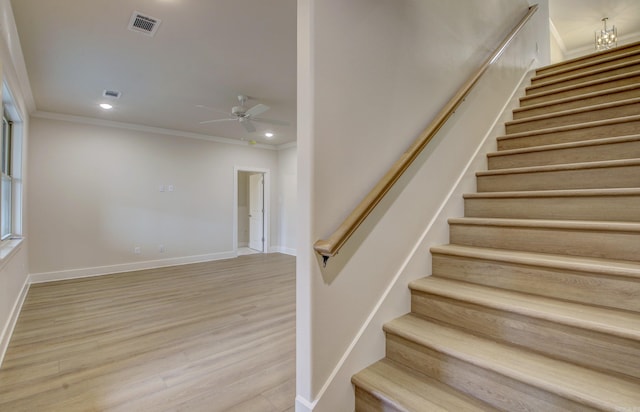 staircase featuring hardwood / wood-style flooring, ceiling fan, and crown molding