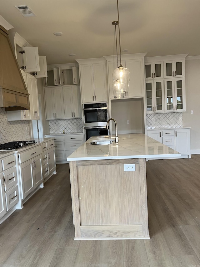 kitchen with backsplash, sink, an island with sink, and pendant lighting