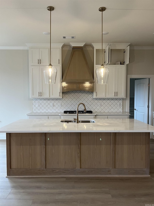 kitchen with light stone countertops, hardwood / wood-style floors, sink, and custom exhaust hood