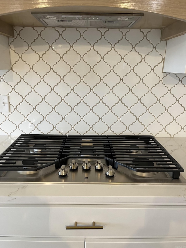 details featuring backsplash, extractor fan, and stainless steel gas stovetop