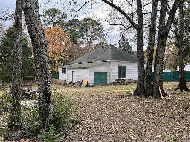 back of house featuring a garage and an outbuilding