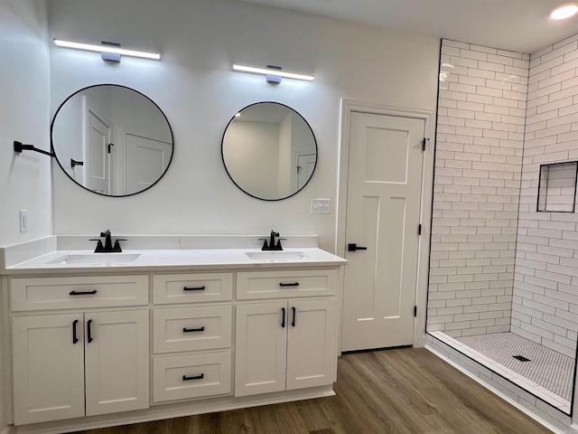 bathroom with hardwood / wood-style flooring, vanity, and tiled shower