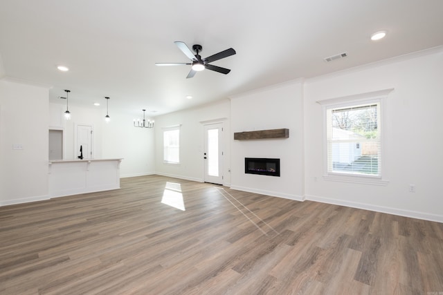 unfurnished living room featuring hardwood / wood-style flooring, ceiling fan with notable chandelier, and ornamental molding