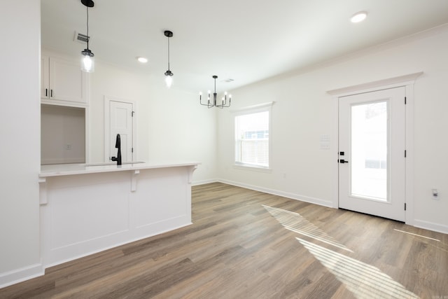 kitchen featuring a breakfast bar, white cabinets, sink, light wood-type flooring, and decorative light fixtures