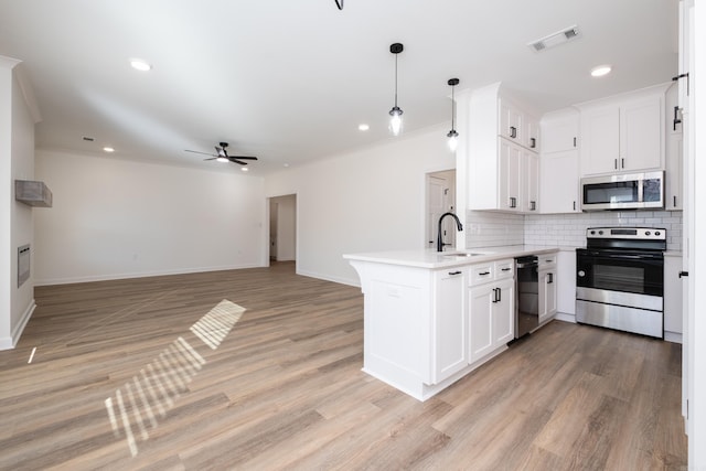 kitchen featuring kitchen peninsula, sink, decorative light fixtures, and appliances with stainless steel finishes