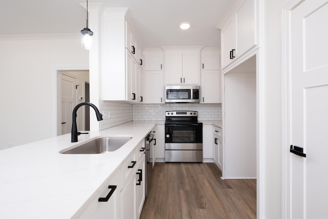 kitchen featuring sink, hanging light fixtures, light stone counters, dark hardwood / wood-style flooring, and stainless steel appliances