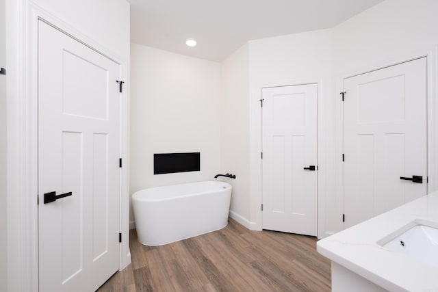 bathroom with a tub to relax in, vanity, and hardwood / wood-style flooring