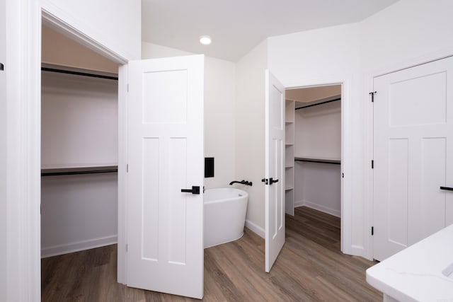 bathroom with wood-type flooring and a tub to relax in