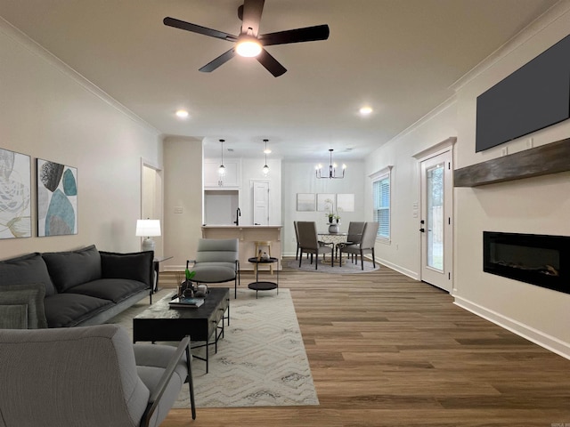 living room featuring ceiling fan with notable chandelier, hardwood / wood-style flooring, and ornamental molding