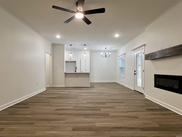 unfurnished living room featuring ceiling fan with notable chandelier, dark hardwood / wood-style flooring, crown molding, and sink