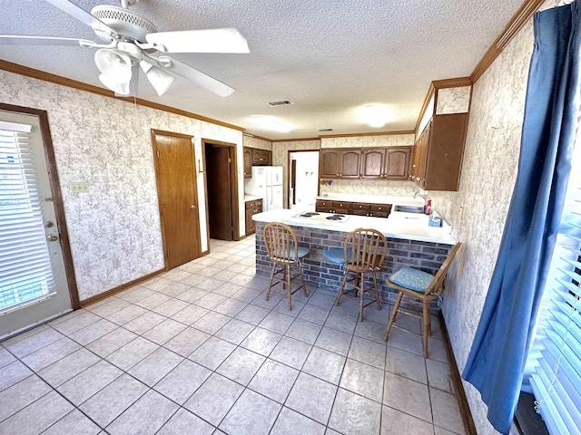 kitchen featuring sink, a kitchen breakfast bar, kitchen peninsula, white appliances, and light tile patterned flooring