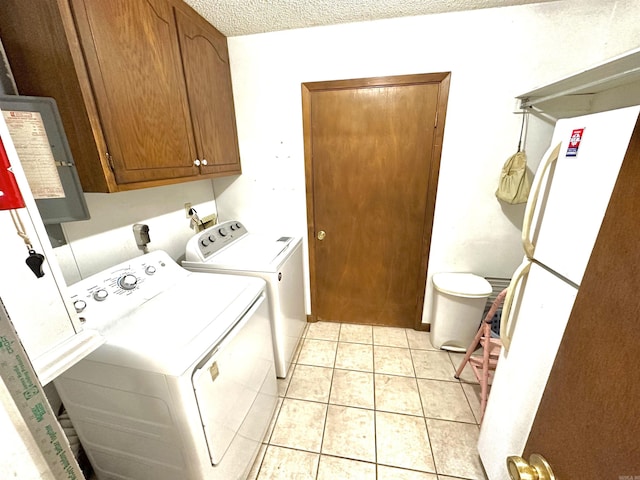 washroom featuring cabinets, light tile patterned flooring, washing machine and dryer, and a textured ceiling