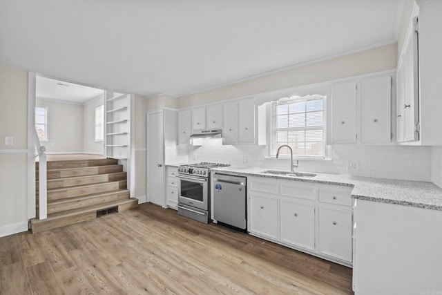 kitchen with backsplash, sink, light hardwood / wood-style flooring, appliances with stainless steel finishes, and white cabinetry